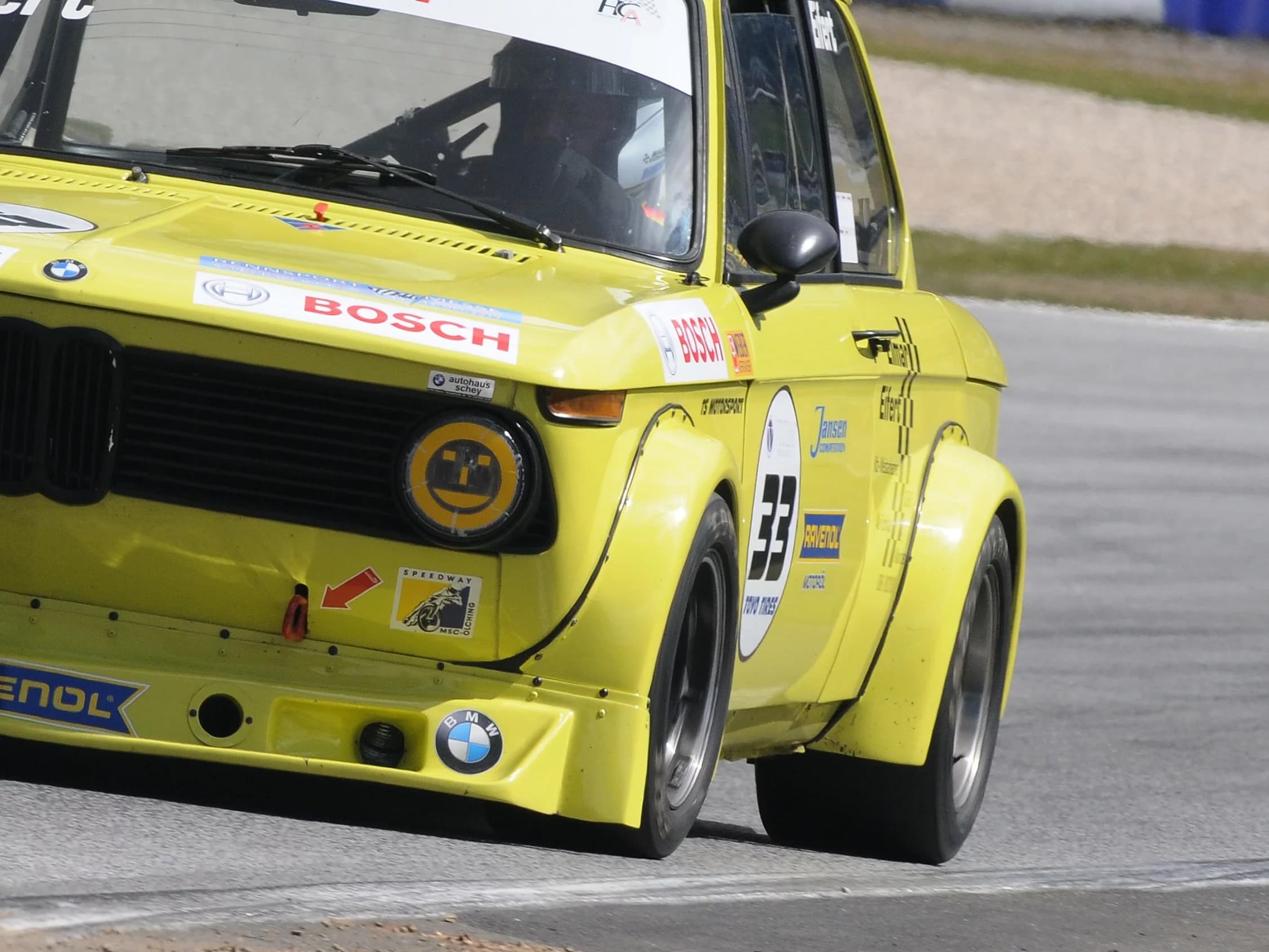 Gelber BMW E10 auf der Rennstrecke mit Detailaufnahme vom Carbon Verbreiterungssatz an der Fahrerseite