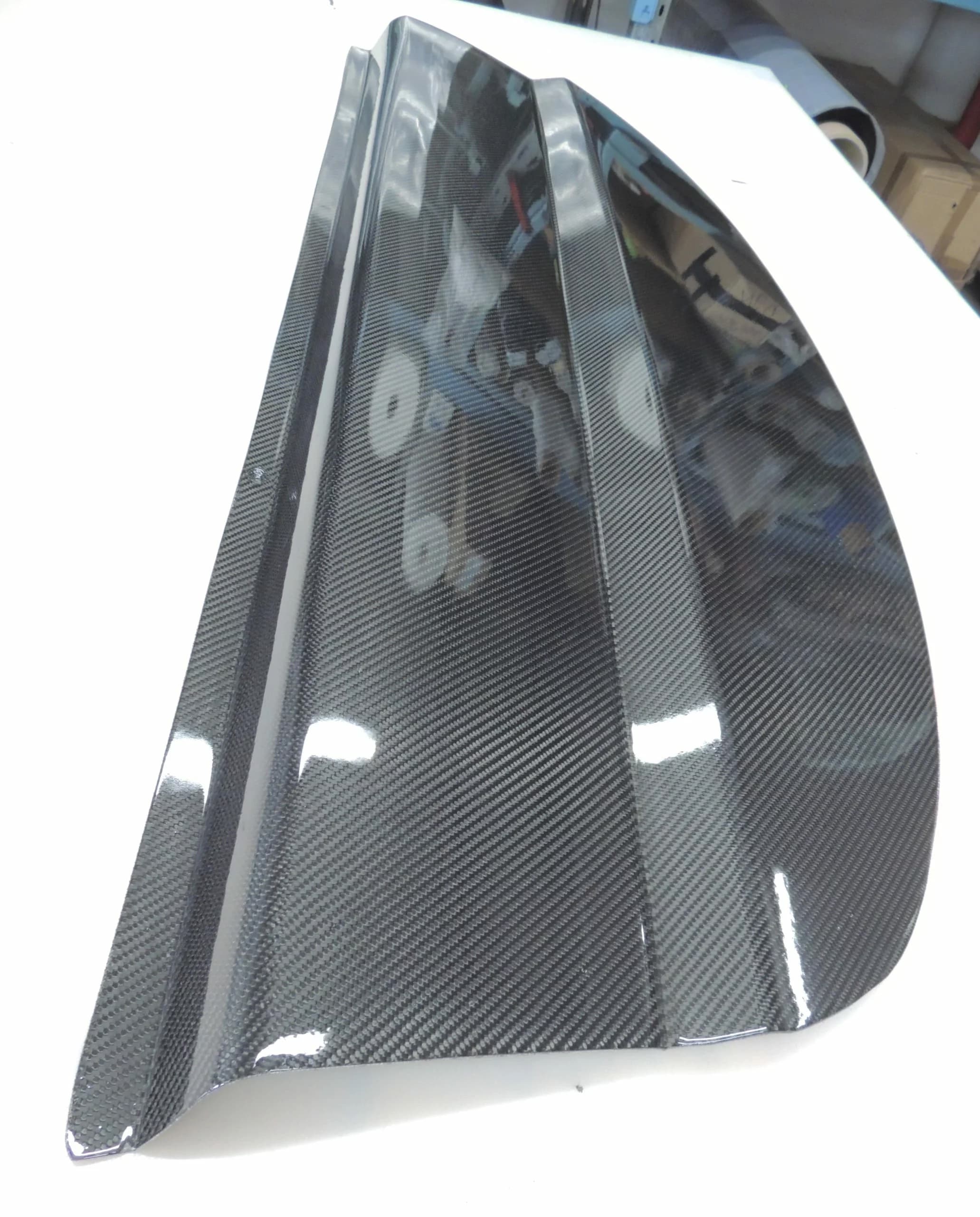Carbon Hutablage BMW E92 in Sichtcarbon, perspektivische Ansicht mit zentraler Sicke und spiegelnder Klarlack-Oberfläche.